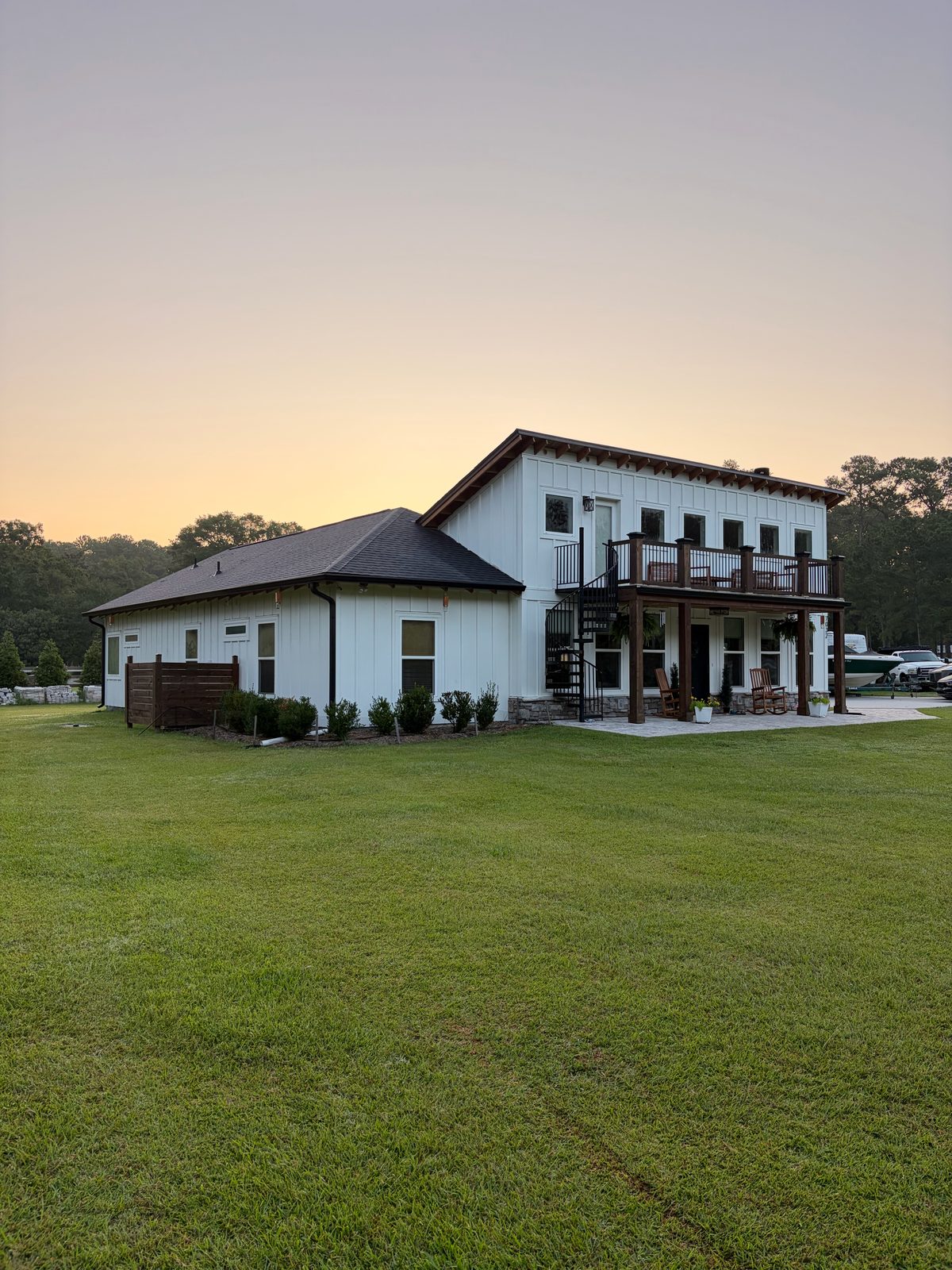 Rear of a white farmhouse with a wood balcony and stone base — a Myrtle Beach job