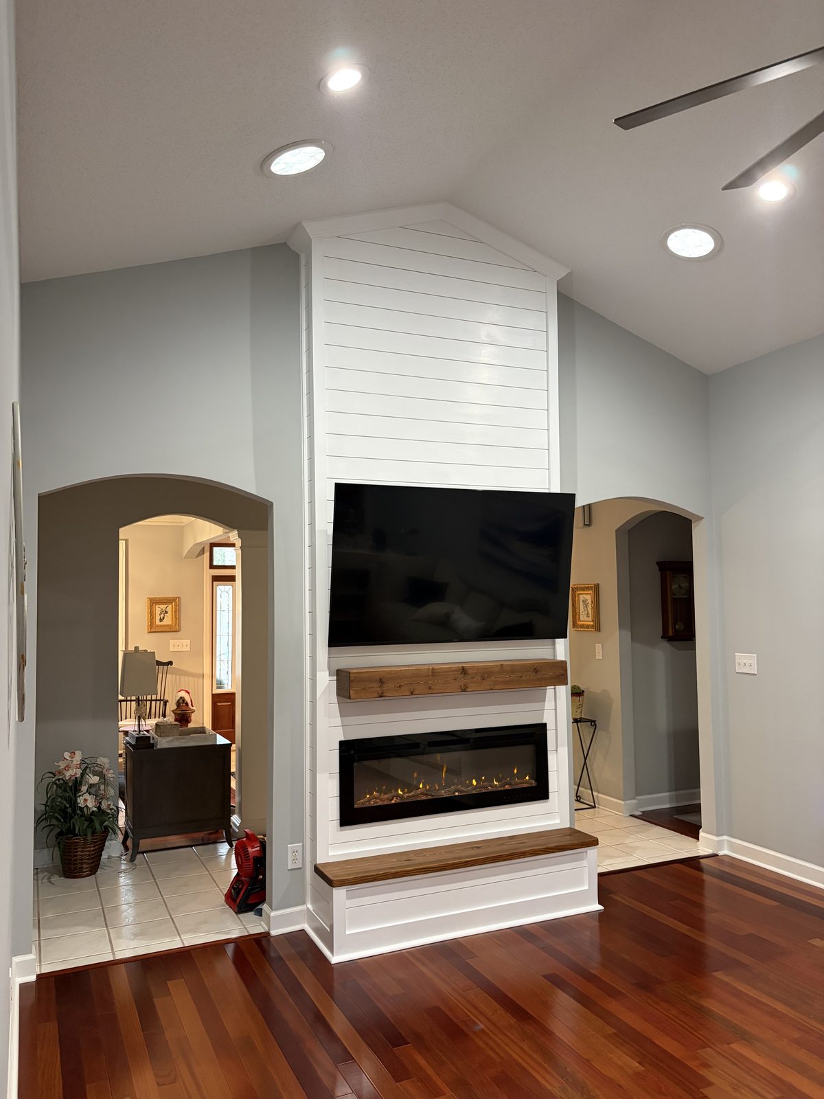White shiplap fireplace and TV wall between arched openings