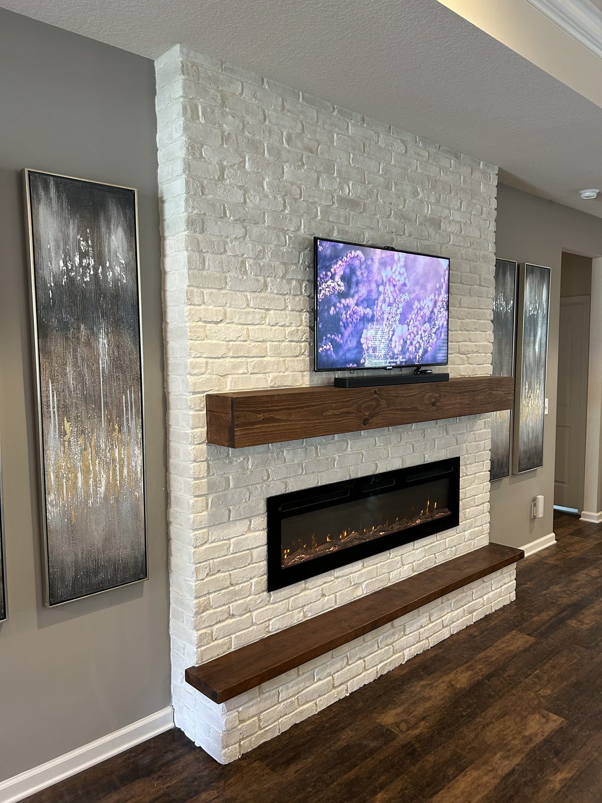 Floor-to-ceiling white brick fireplace and TV wall with a dark wood mantel and hearth