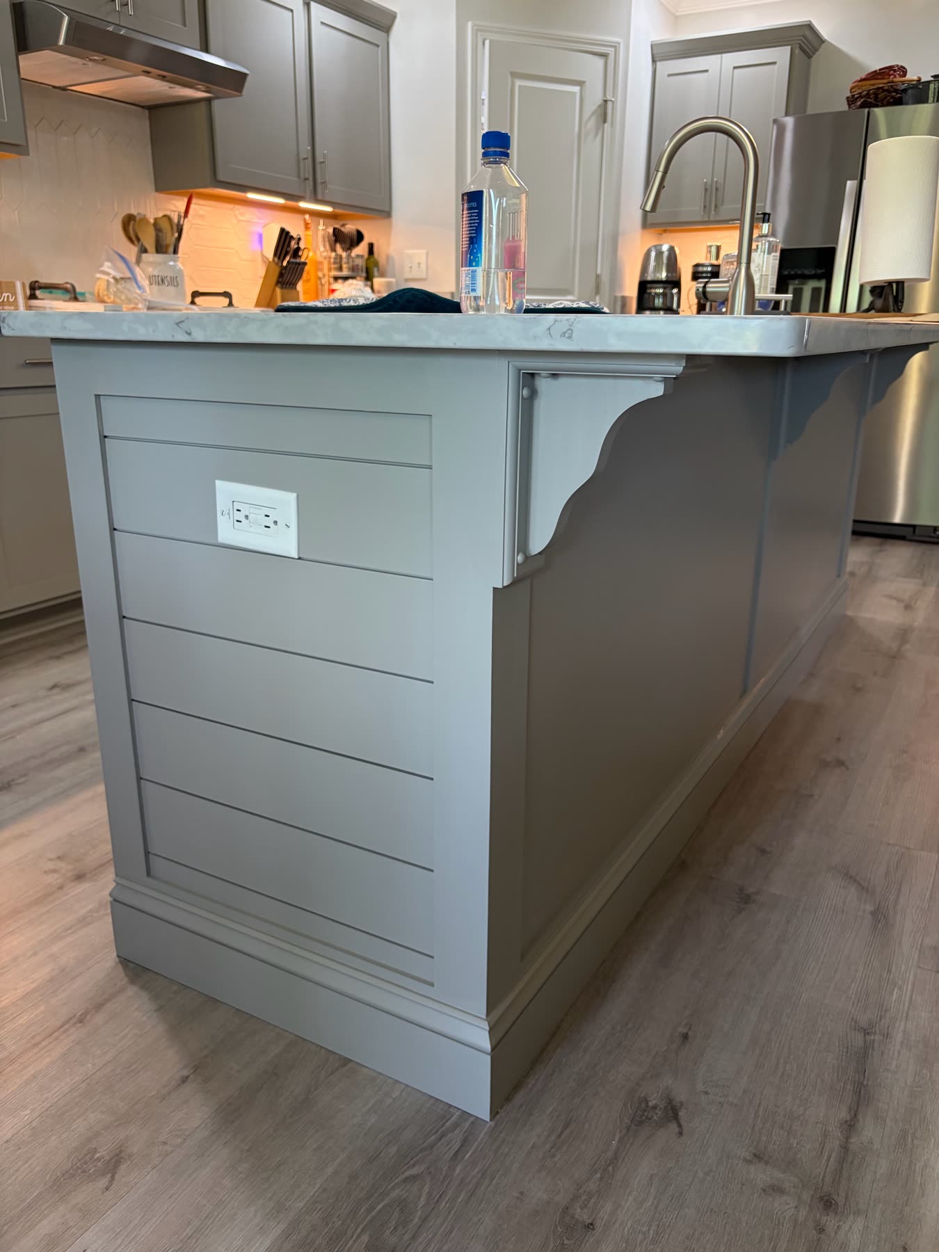 Gray shiplap kitchen island end panel with decorative corbels and a white quartz counter