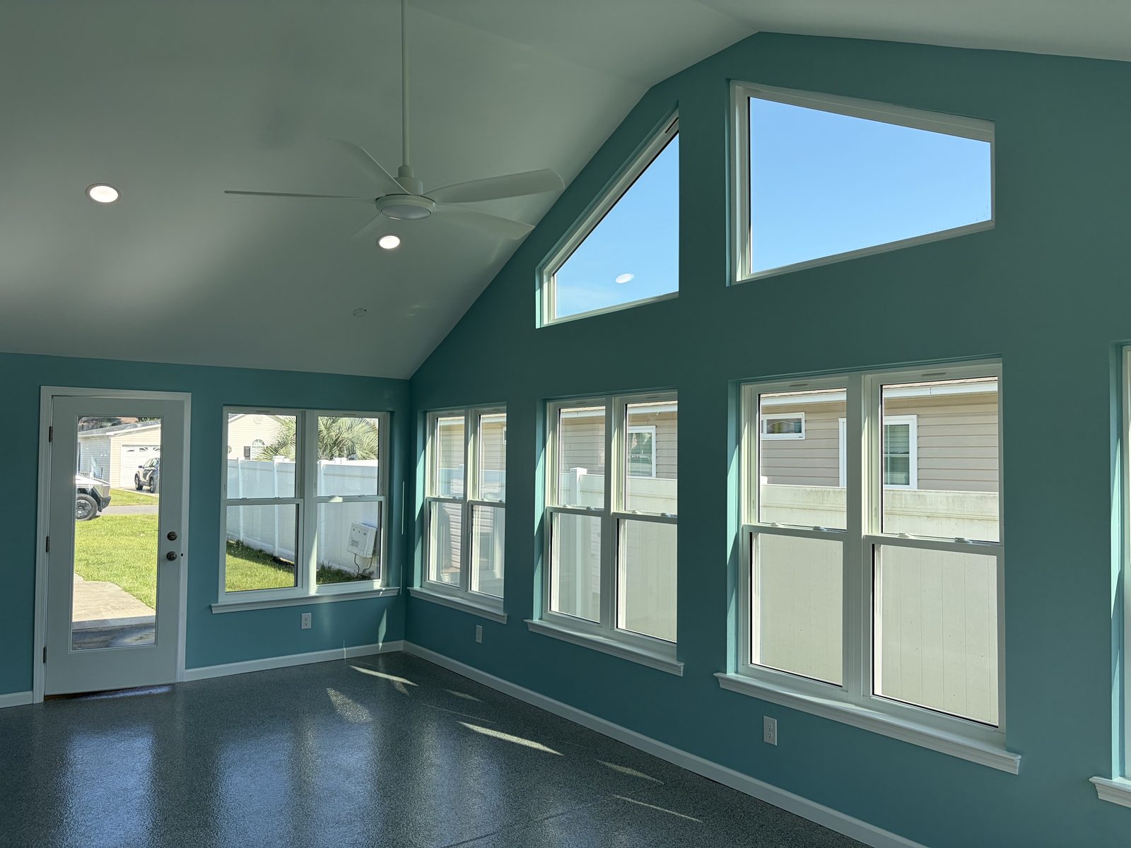 Sunroom addition with a vaulted gable ceiling, trapezoid gable windows, and a ceiling fan