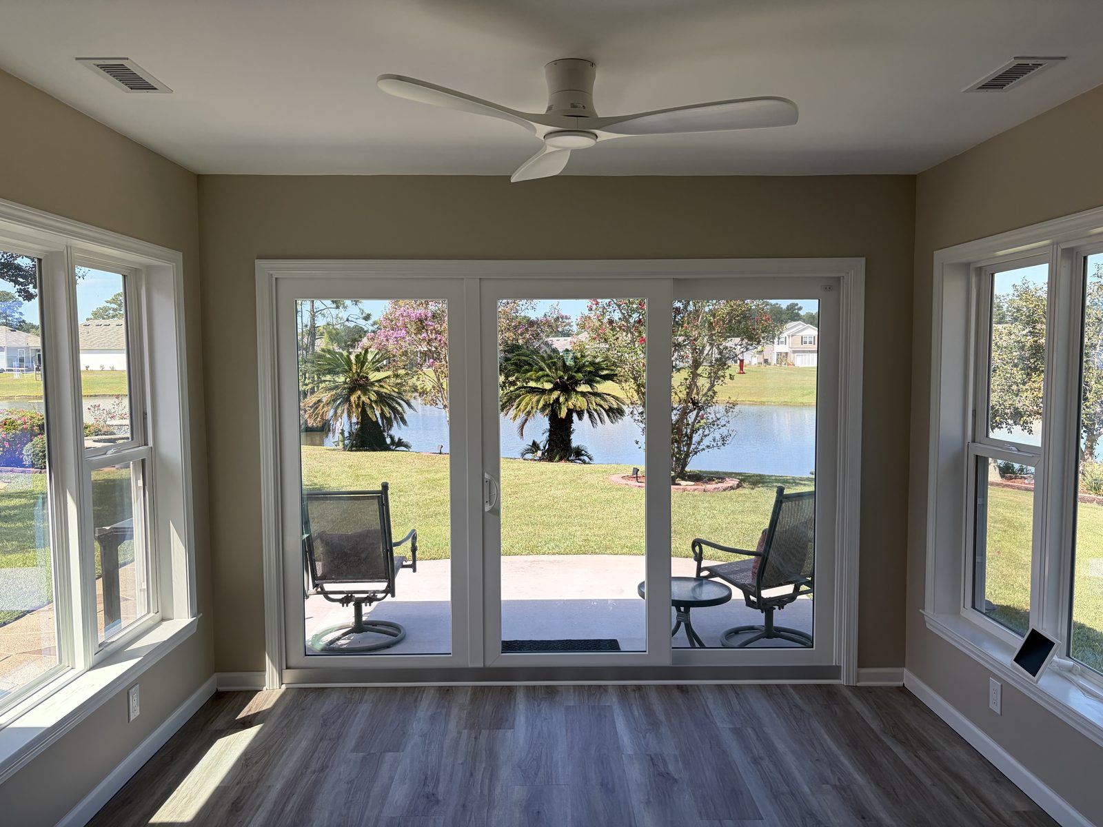 Sunroom with a sliding glass door looking out on a pond and palm trees
